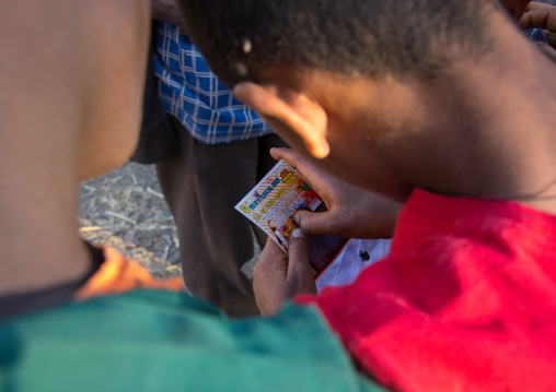 Ethiopian child playing a scratch-off lottery, Amhara region, Lalibela, Ethiopia