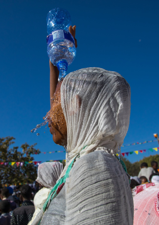 Ethiopian pilgrim woman putting some holy water on her face during Timkat epiphany festival, Amhara region, Lalibela, Ethiopia
