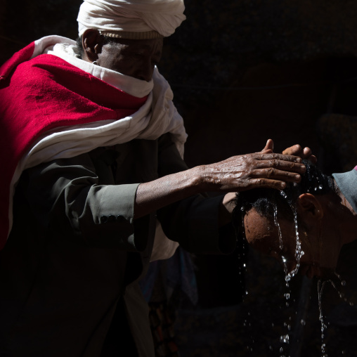 Priest of the ethiopian orthodox church blessing a pilgrim with holy water for Timkat, Amhara region, Lalibela, Ethiopia