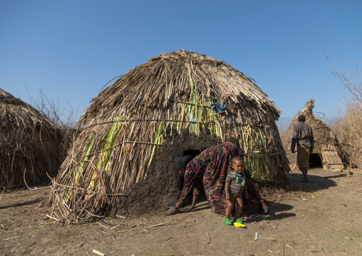 Artuma tribe woman putting some mud around her hut entrance, Amhara region, Kemise, Ethiopia