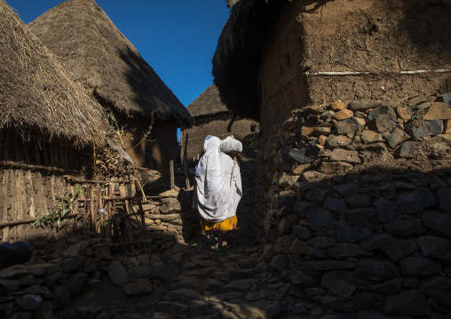 Ethiopian woman walking in a stone houses village in the highlands, Amhara region, Debre Birhan, Ethiopia