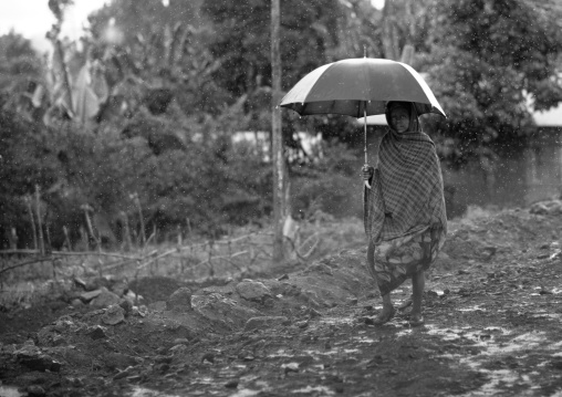Woman with umbrella walking in the mud, Ethiopia