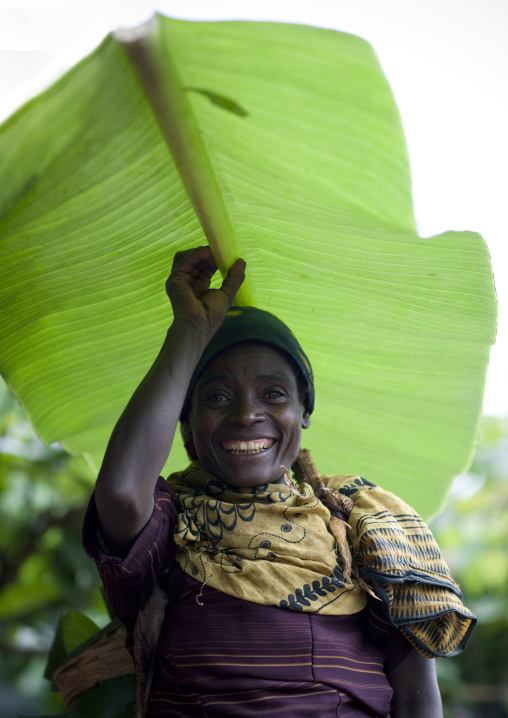 Benje woman using a huge leaf as an umbrella, Ethiopia