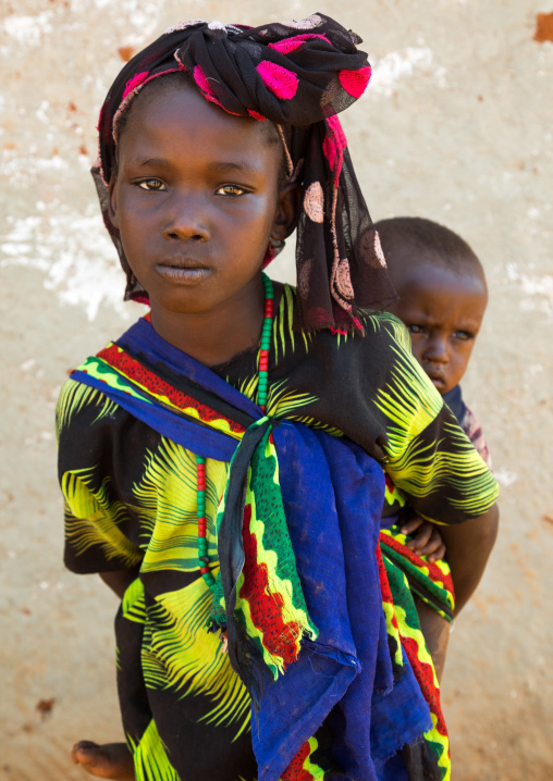 Portrait of a Borana tribe girl carrying her brother on her back, Oromia, Yabelo, Ethiopia