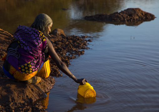 Borana tribe woman filling jerricans in a water reservoir used for animals, Oromia, Yabelo, Ethiopia