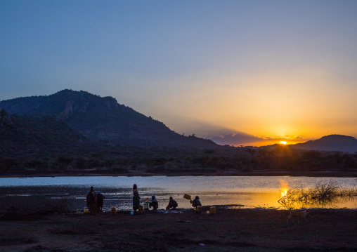 Sunset over Borana tribe people filling jerricans in a water reservoir used for animals, Oromia, Yabelo, Ethiopia