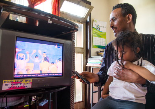 Pastor Mohamed Ousman Salih who converted from islam to christianity watching a religious channel on television with his daughter, Addis Ababa region, Addis Ababa, Ethiopia