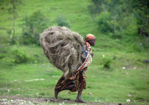Benje woman carrying a bunch of straw, Ethiopia