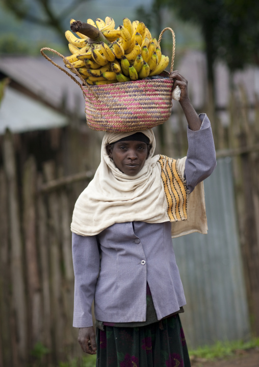 Veiled woman carrying a basket of bananas on her head, Ethiopia