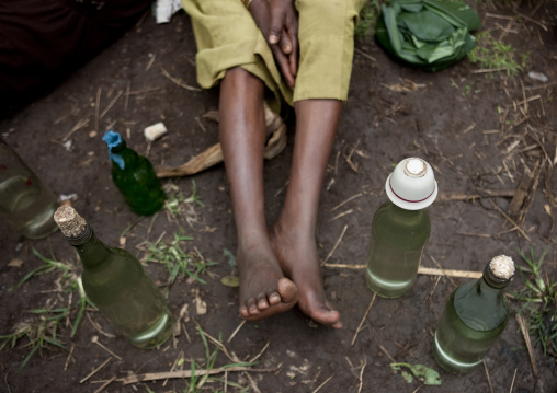 Legs between alcohol bottles, Tum market, Omo valley, Ethiopia