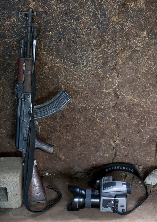 Kalashnikov And Camera Leaning On A Wall, Turgit Village, Omo Valley, Ethiopia