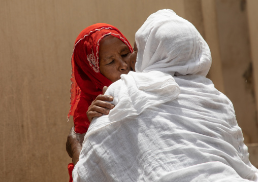 Muslim woman kissing an orthodox woman in the street, Harari region, Harar, Ethiopia