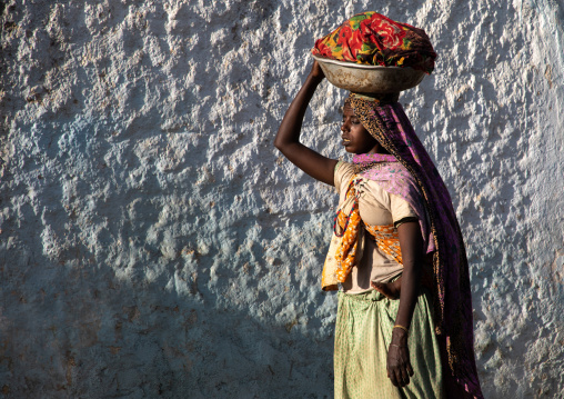 Ethiopian woman carrying a basket on her head in the streets of the old town, Harari region, Harar, Ethiopia