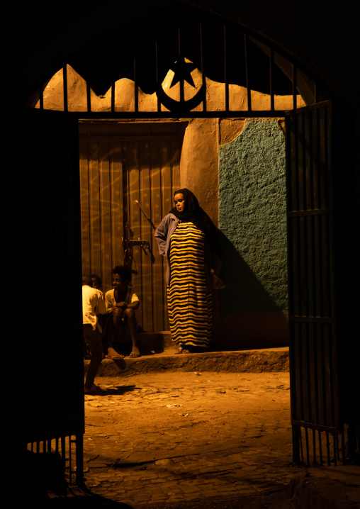 Harari woman at the entrance of a holy shrine at night, Harari region, Harar, Ethiopia