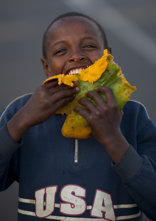 Boy eating a papaya fruit, Gourague, Area, Ethiopia
