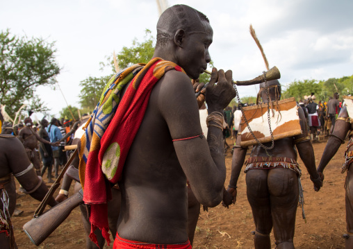 Man blowing in a horn during Bodi tribe fat men during Kael ceremony, Omo valley, Hana Mursi, Ethiopia