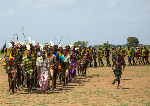 Men running in line with weapons during the proud ox ceremony in the Dassanech tribe, Turkana County, Omorate, Ethiopia
