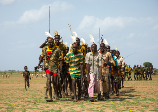 Men running in line with weapons during the proud ox ceremony in the Dassanech tribe, Turkana County, Omorate, Ethiopia