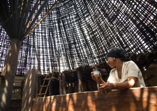 Woman drinking a coffee under a Gurage traditional roof without thatch in renovation, Gurage Zone, Butajira, Ethiopia