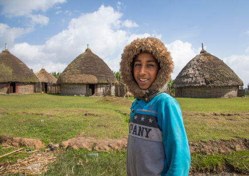 Boy with a rain hood in front of a Gurage traditional houses with thatched roofs, Gurage Zone, Butajira, Ethiopia