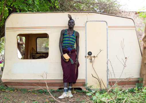 Sudanese Toposa tribe man refugee in front of an old abandonned caravan, Omo Valley, Kangate, Ethiopia