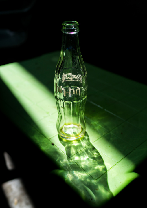 Ethiopian coca cola bottle in a ray of light in a bar, Omo Valley, Kangate, Ethiopia