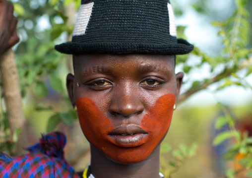 Beautiful young woman with a hat and some make up during the fat men ceremony in the Bodi tribe, Omo valley, Hana Mursi, Ethiopia