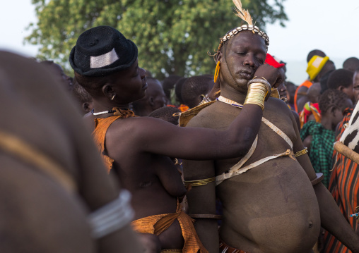 Woman wiping the sweat of a Bodi tribe fat man during Kael ceremony, Omo valley, Hana Mursi, Ethiopia