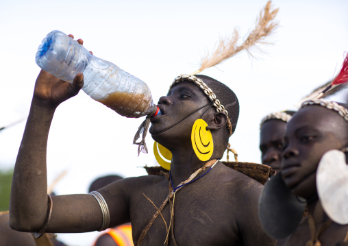 Bodi tribe fat man drinking milk during Kael ceremony, Omo valley, Hana Mursi, Ethiopia
