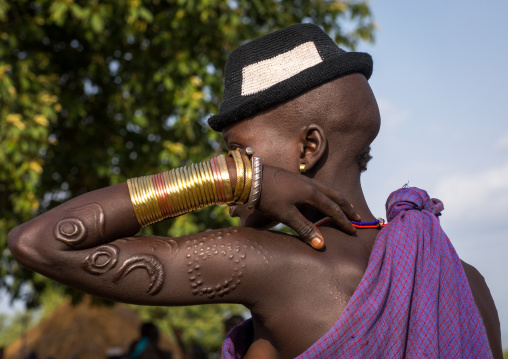 Beautiful young woman with a hat and bracelets during the fat men ceremony in the Bodi tribe, Omo valley, Hana Mursi, Ethiopia