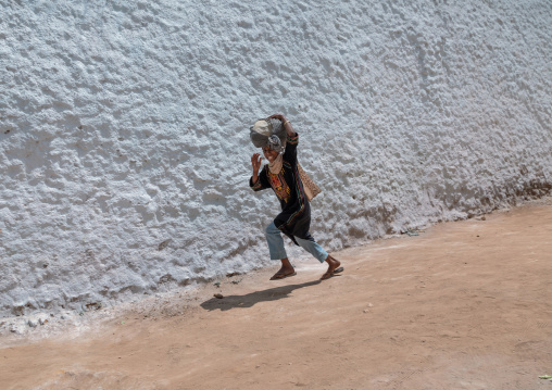 Harari girl running in front of a white wall, Harari Region, Harar, Ethiopia
