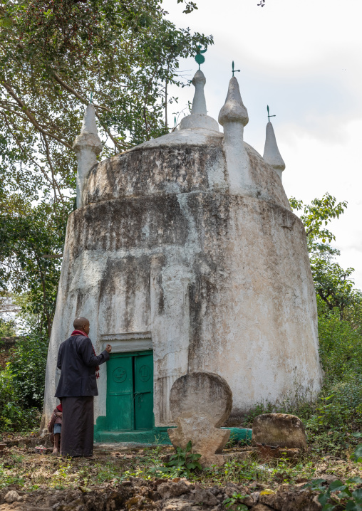 Harari man praying in front of an old muslim grave, Harari Region, Harar, Ethiopia