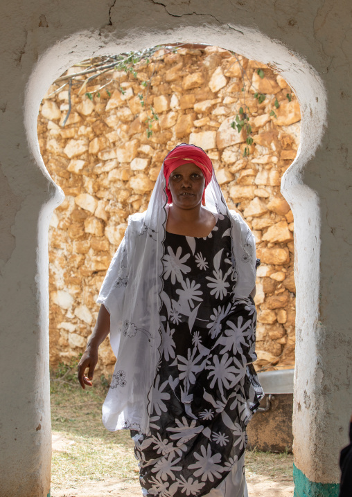 Harari woman going thru a door with an arabic shape, Harari Region, Harar, Ethiopia