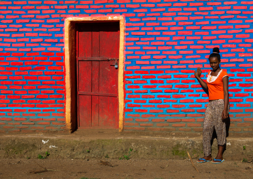 Ethiopian woman standing in front of colorful brick wall, Bench Maji, Mizan Teferi, Ethiopia