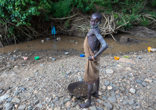 Suri tribe girl doing gold panning in a river, Omo valley, Kibish, Ethiopia