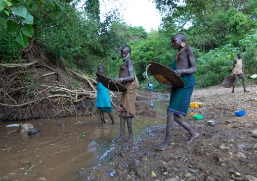 Suri tribe girls doing gold panning in a river, Omo valley, Kibish, Ethiopia