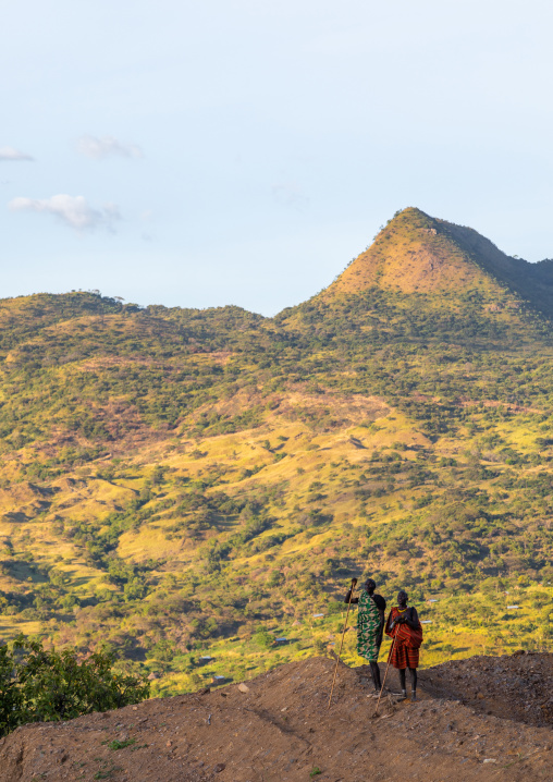 Suri tribe couple in front of a mountain landscape, Omo valley, Kibish, Ethiopia
