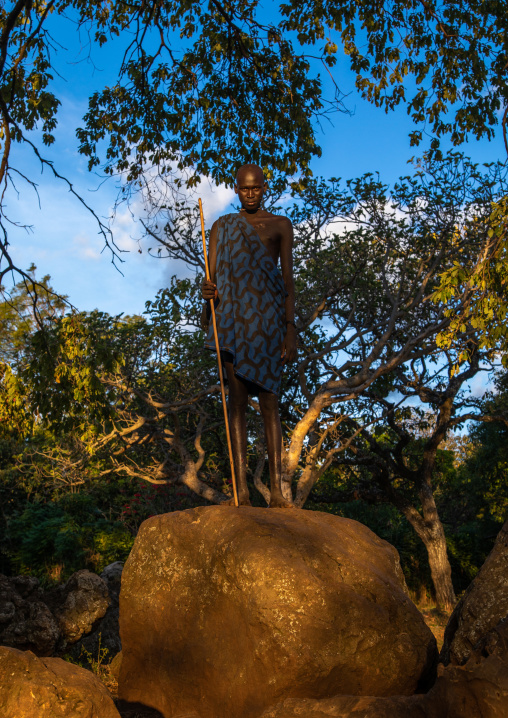 Suri tribe man standing on a giant rock in a sunny light, Omo valley, Kibish, Ethiopia