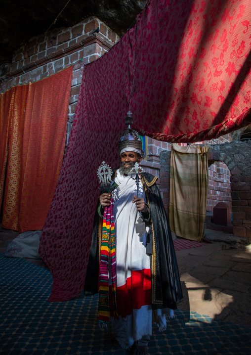 Ethiopian orthodox priest in nakuto lab rock church holding a cross, Amhara Region, Lalibela, Ethiopia