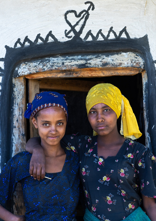 Raya tribe gilrs at the entrance of a decorated hut, Afar Region, Chifra, Ethiopia