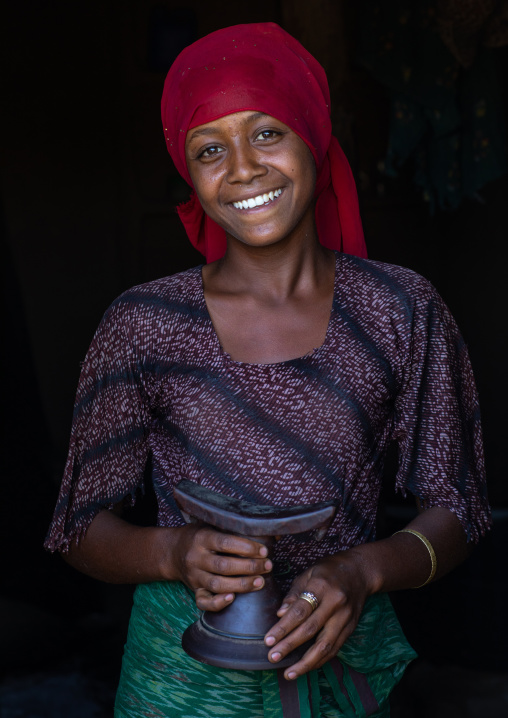 Portrait of a smiling raya tribe girl holding a wooden pillow, Afar Region, Chifra, Ethiopia