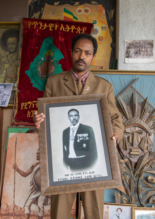 Secretary of the patriots in the war museum holding a picture of his father, Addis Abeba region, Addis Ababa, Ethiopia