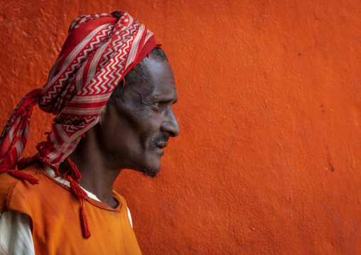 Portrait of an ethiopian muslim man in front of an orange wall, Oromia, Hirna, Ethiopia