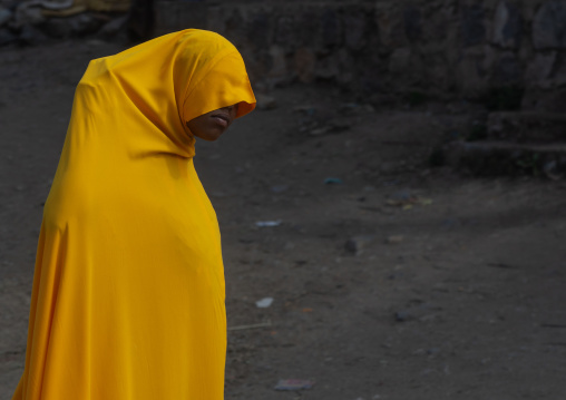 Ethiopian woman in yellow burqa walking in the street, Oromia, Karamile, Ethiopia