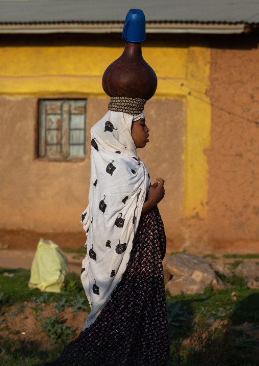 Ethiopian woman walking in the street with a pot on her head, Harari Region, Harar, Ethiopia