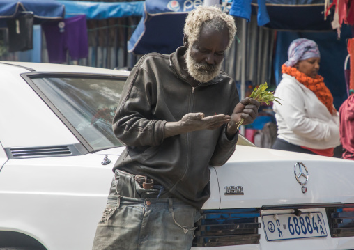 Senior ethiopian man leaning on a Mercedes car while chewing his khat leaves, Addis Ababa Region, Addis Ababa, Ethiopia