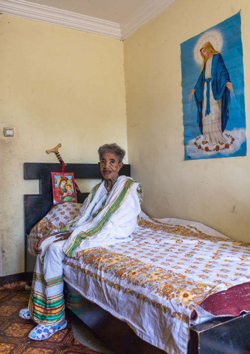 Ethiopian woman in her bedroom below a virgin mary poster, Addis Ababa Region, Addis Ababa, Ethiopia