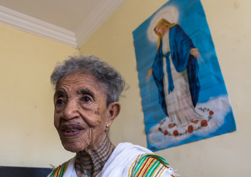 Ethiopian woman in her bedroom below a virgin mary poster, Addis Ababa Region, Addis Ababa, Ethiopia