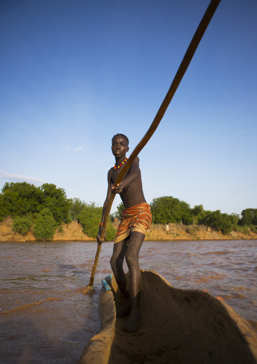 Young Boy Pushing A Boat On The Omo River, Omorate, Omo Valley, Ethiopia