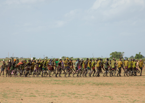 Men running in line with weapons during the proud ox ceremony in the dassanech tribe, Turkana County, Omorate, Ethiopia